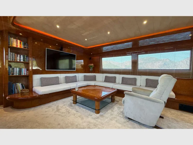 Admiral 115 Poseidon charter motor yacht interior saloon seating area with TV and a recliner armchair with extendable footrest