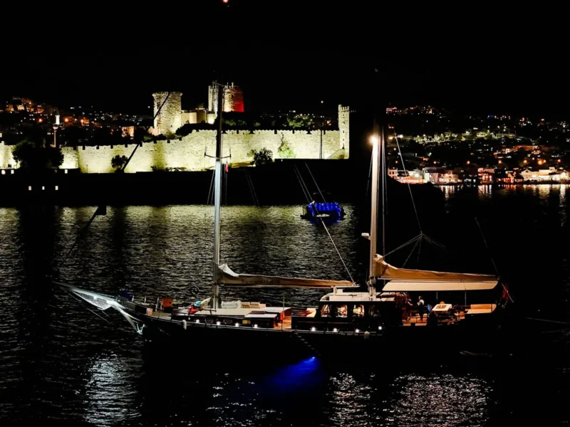 Sunworld 8 gulet charter yacht Bodrum, drone shot from port side at night, Bodrum Castle on the background